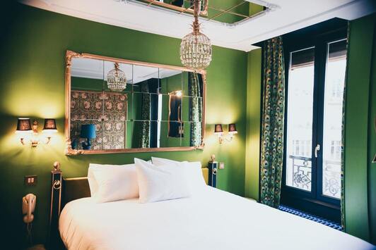Image de la chambre d'hôtel montrant un lit avec les murs vert