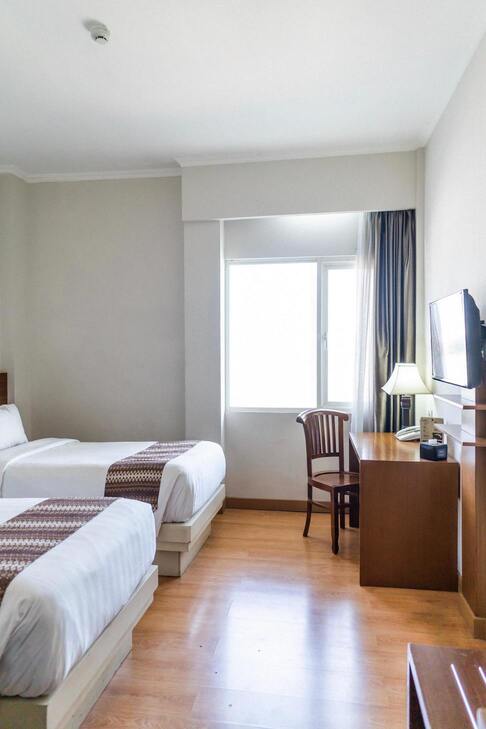 Image de la chambre d'hôtel montrant deux lits et un sol marron